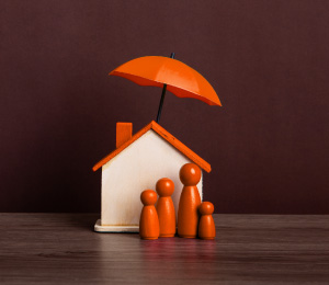 Sombrilla protege una casa, simbolizando el seguro de desgravamen y la seguridad financiera del hogar.