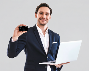 Hombre sonriente con gafas sosteniendo la tarjeta de crédito premium y una tablet blanca sobre fondo gris.