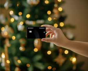 Primer plano de mano sosteniendo una tarjeta de crédito frente a luces de Navidad desenfocadas.
